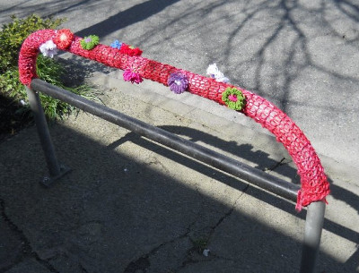 Bike rack covered with colorful, yarn-bombed flowers