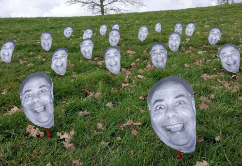Dozens of face printouts of Wassa stuck into a green lawn